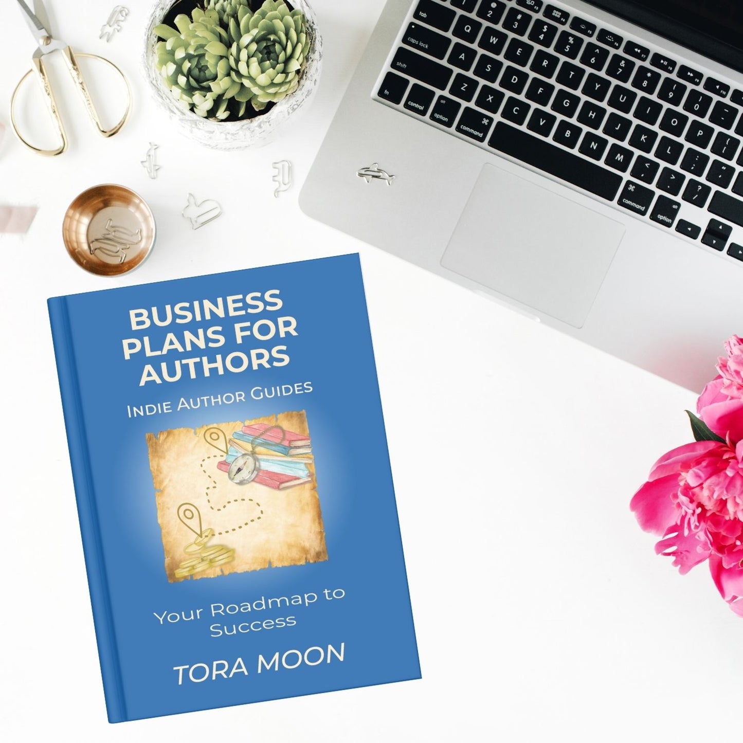 Business Plans for Authors print book by Tora Moon styled on a desk with laptop, flowers, and author tools. Practical indie author business planning guide.