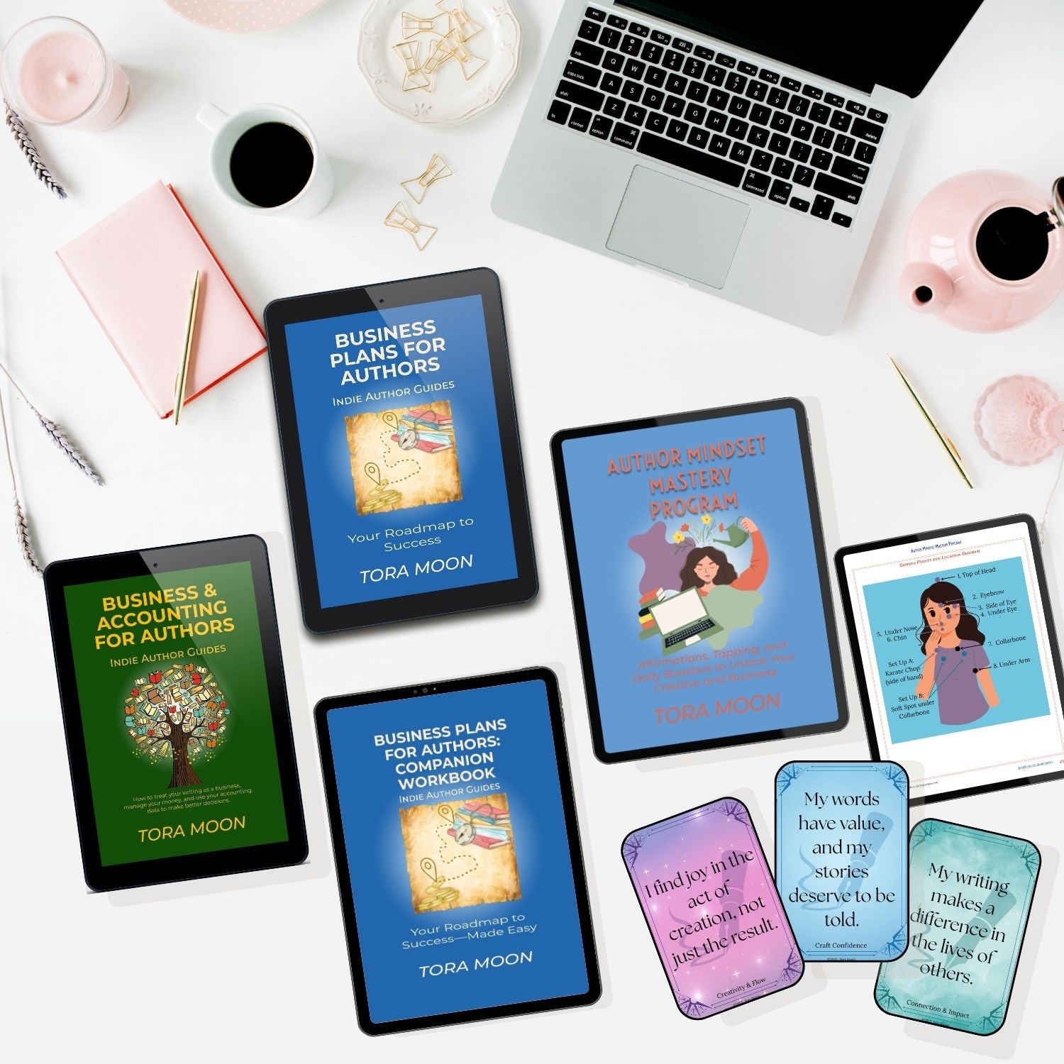 Flat-lay lifestyle image showing the complete Indie Author Business System by Tora Moon, including the Business Plans for Authors guide, Business & Accounting for Authors, the Author Mindset Mastery Program, the companion workbook, and affirmation cards displayed on tablets and devices on a creative author desk.