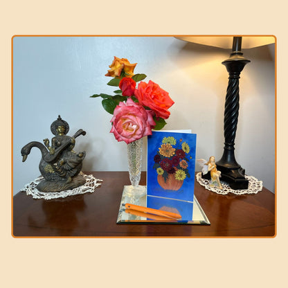 Pumpkin Bouquet floral note card displayed on a wooden table beside a vase of roses, pen, and lamp. A cozy lifestyle photo from Tora Moon’s Blooming Expressions note card collection, perfect for fall greetings or thank-you notes.