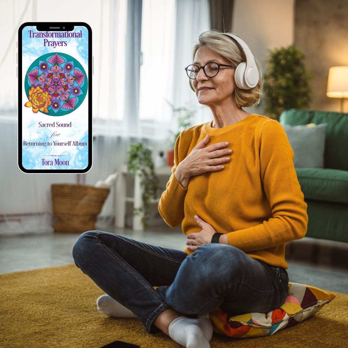 Woman seated with headphones and one hand over her heart while listening to the Sacred Sound Sanskrit mantra album on her phone.