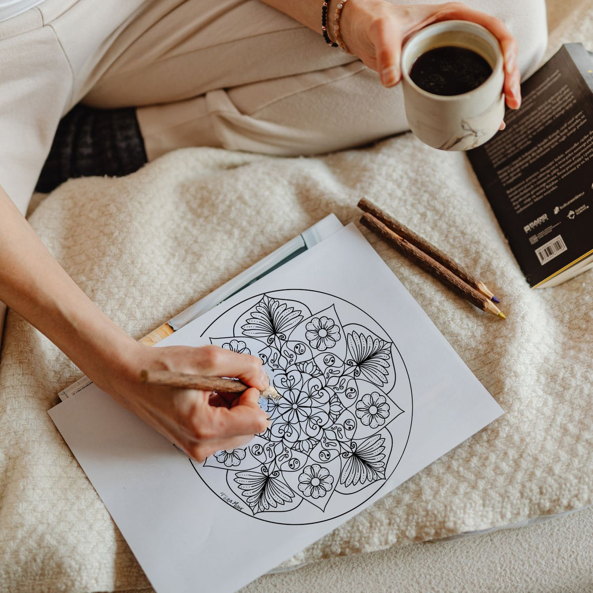 Woman coloring a printed original mandala by Tora Moon with colored pencils, showing how the digital Transformational Prayers Mandala Coloring Book can be printed and colored by hand.